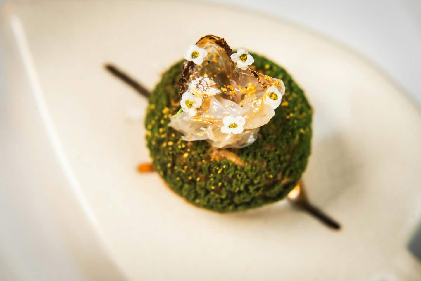 Dolce gourmet con scaglie d'oro e fiori di zucchero.
