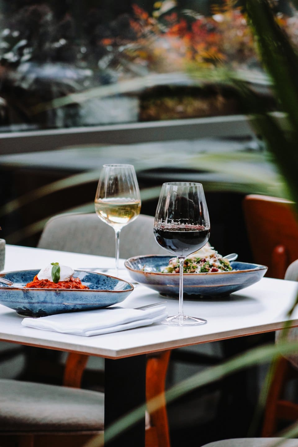 Due piatti gourmet con vino su un tavolo bianco.