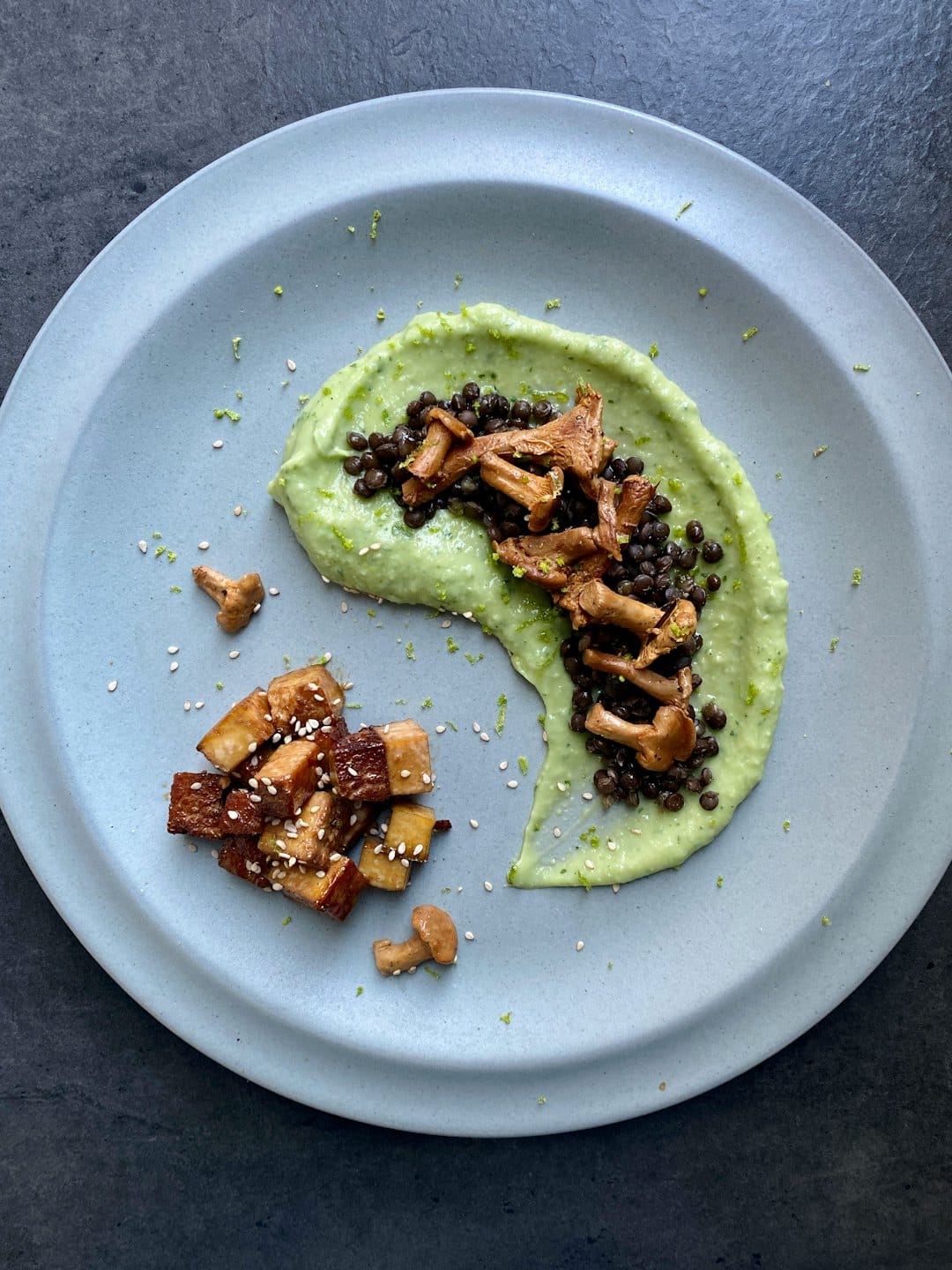 Vista aerea di un pasto vegano con purè verde, funghi e tempeh.