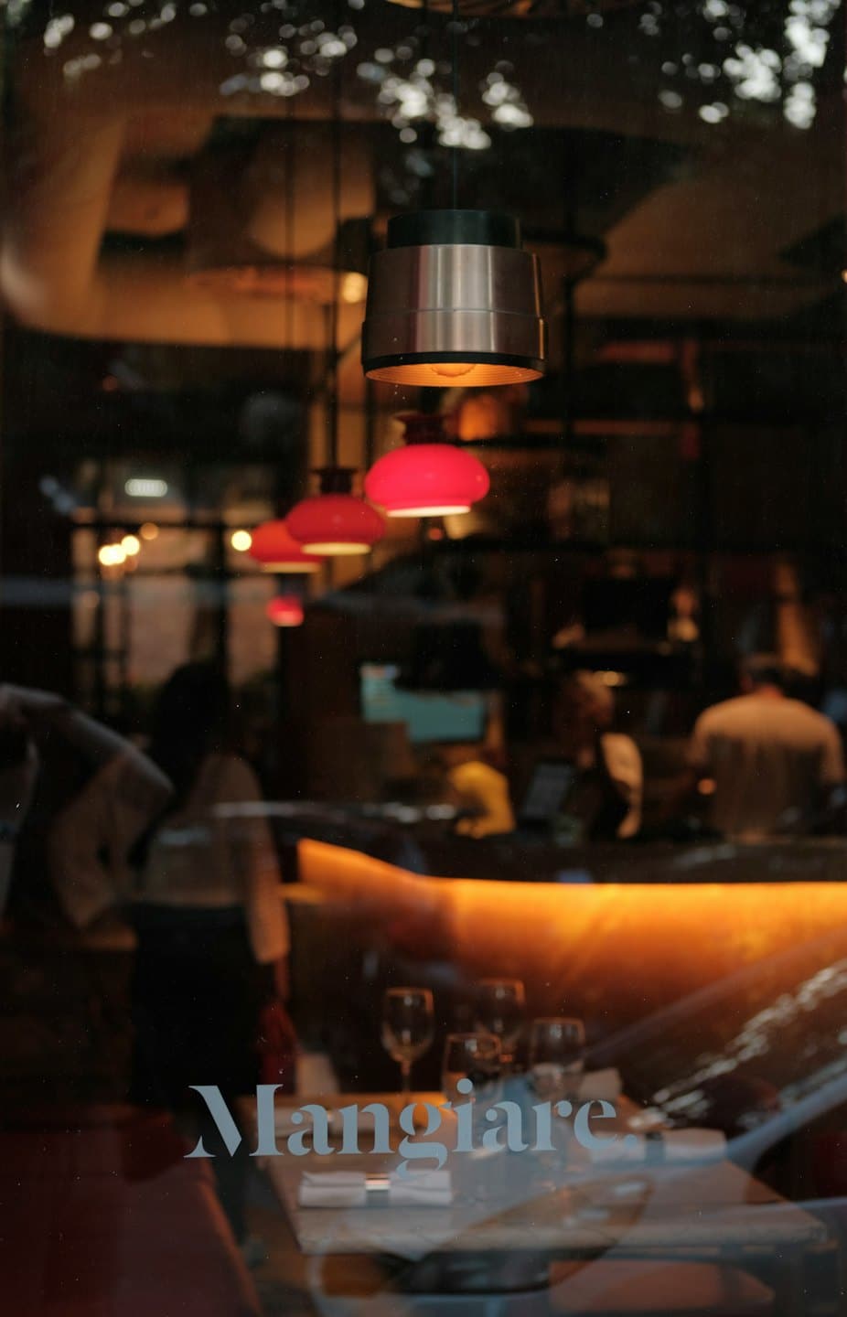 Lampade a sospensione rosse pendono in una sala da pranzo poco illuminata di un ristorante.